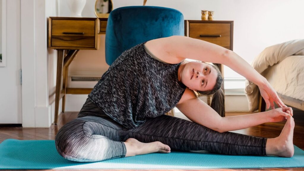 Femme en étirement sur un tapis dans un salon clair