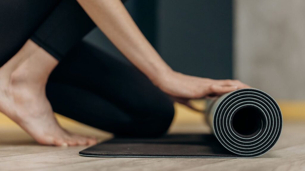 Tapis de yoga roulé posé sur un parquet