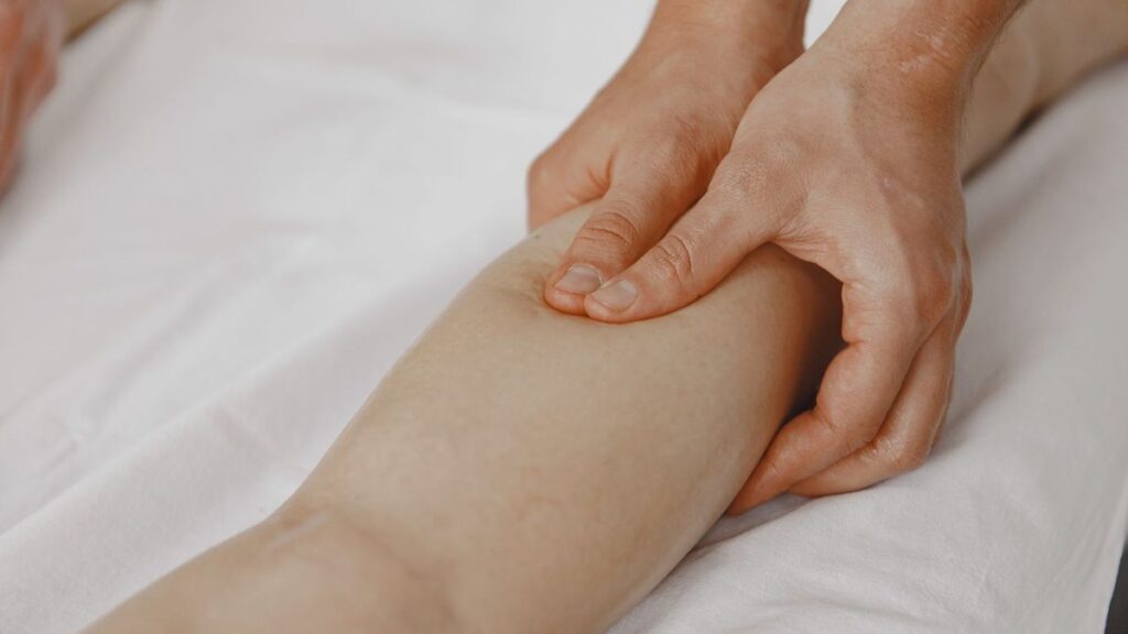 Mains à plat massant une jambe lentement