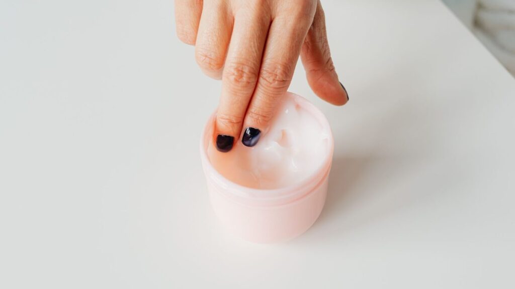 Texture de crème étalée entre les doigts